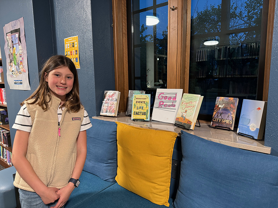 Teen girl smiling. next to the Teen Board Book Display