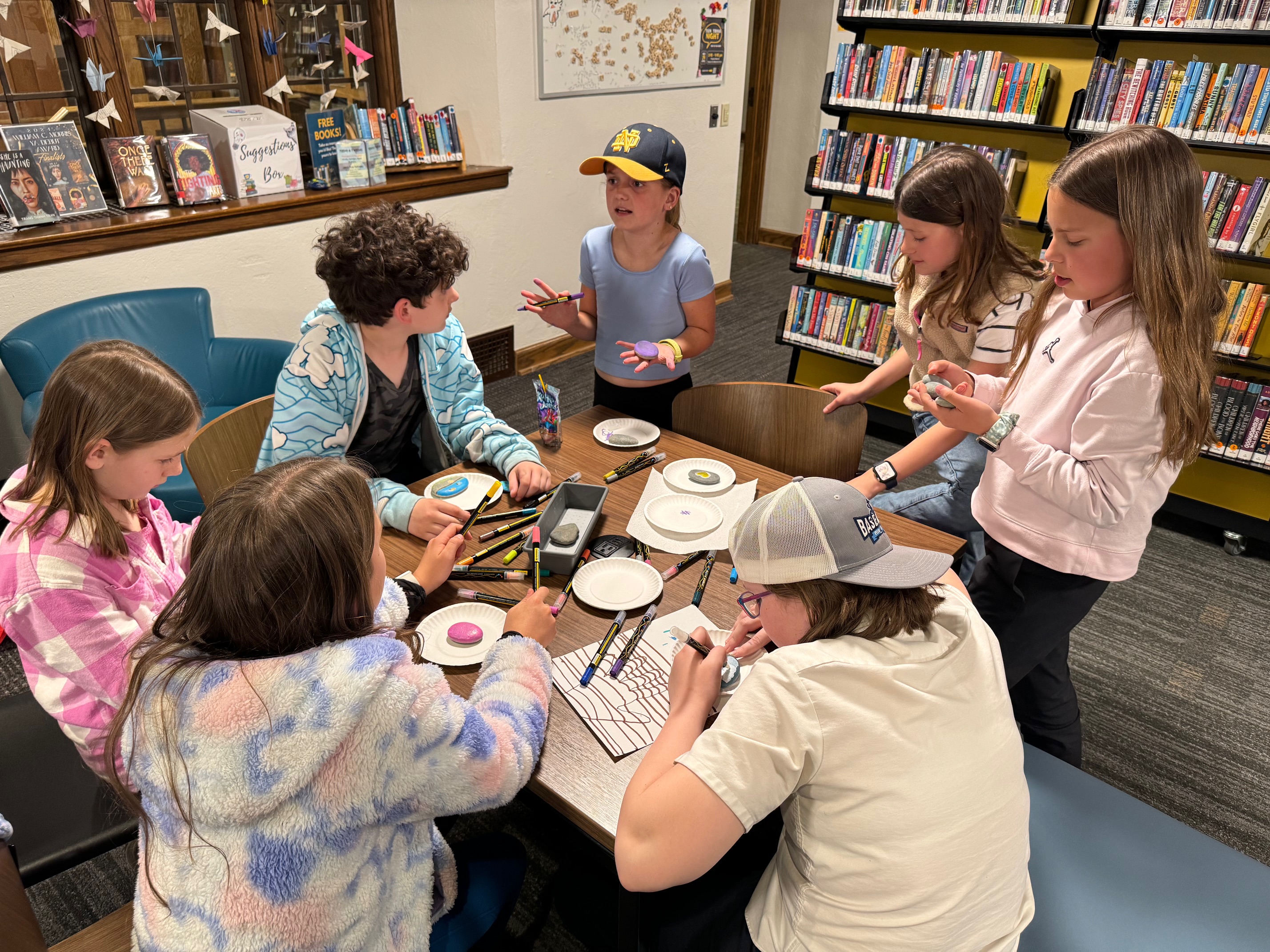 Seven teens talking in the library during a teen board meeting