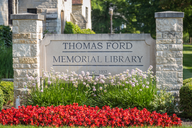 Stone sign embossed with "Thomas Ford Memorial Library" surrounded by flowers