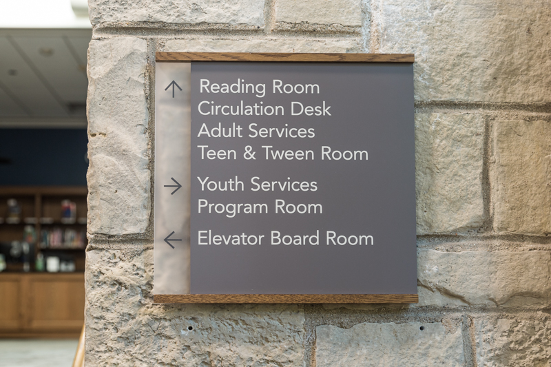 Closeup of wayfinding sign posted to pillar inside the library