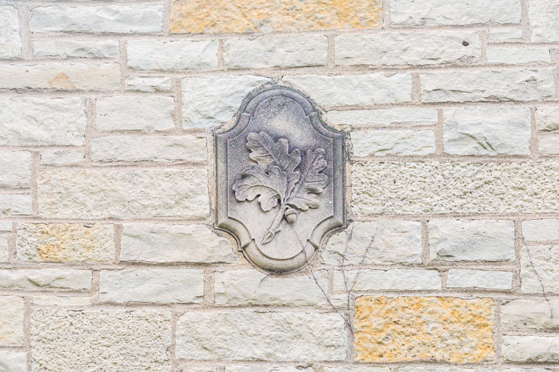 Stone icon affixed to side of building with oak leaf and acorn motif