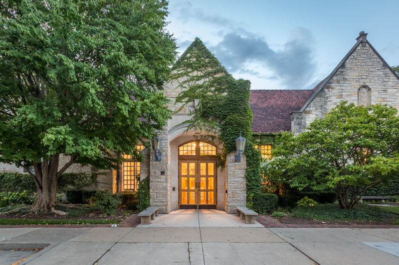 Library front entrance and lit windows against cloudy sky and foliage