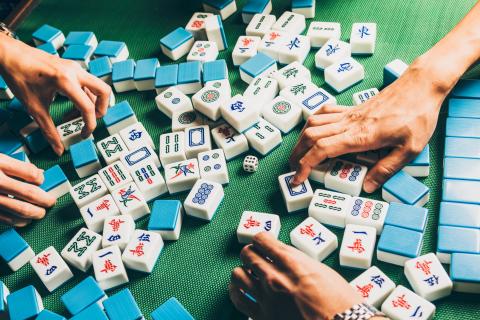 Photo of two pairs of hands sorting through mah-jongg tiles