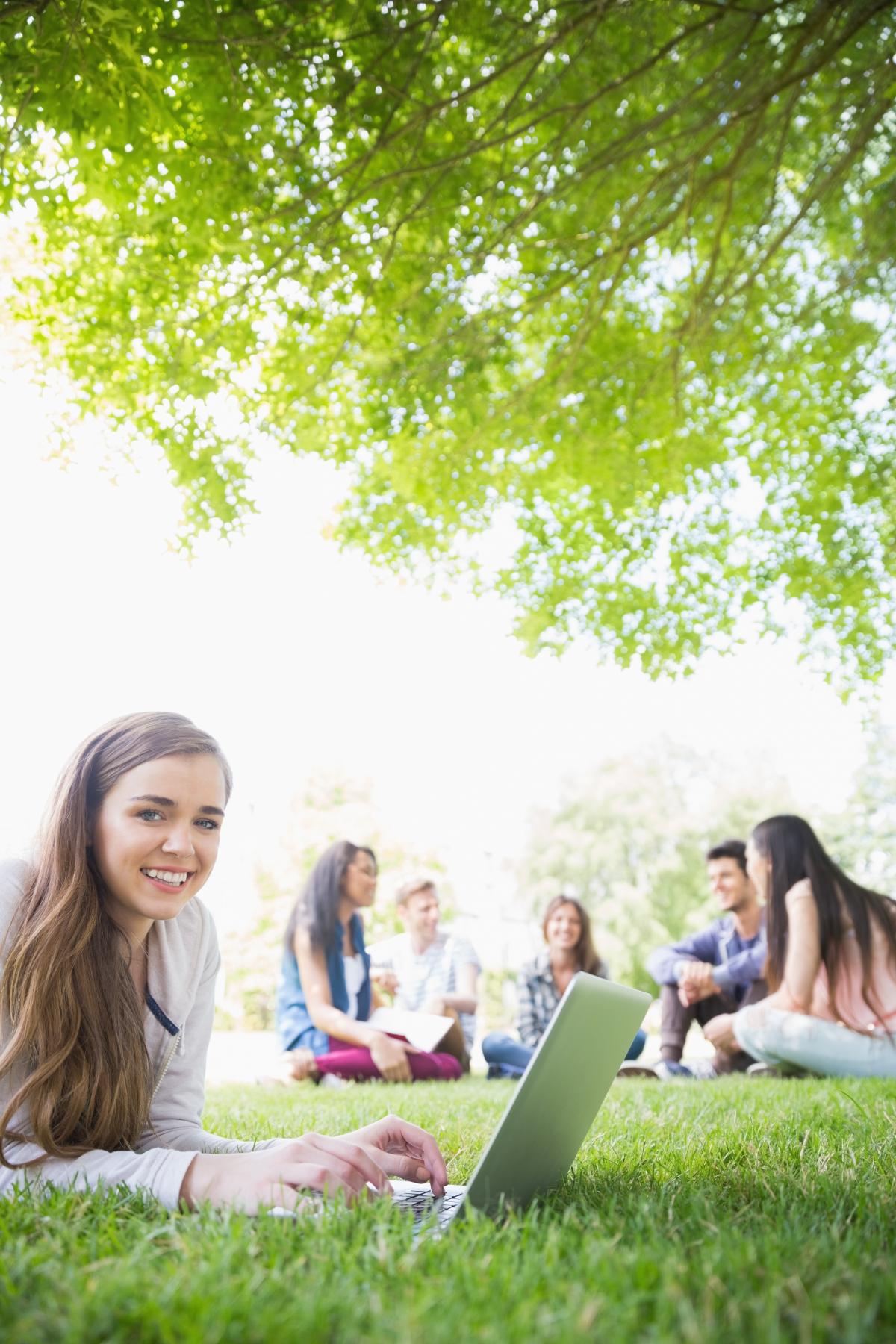 Teens on laptops outdoors